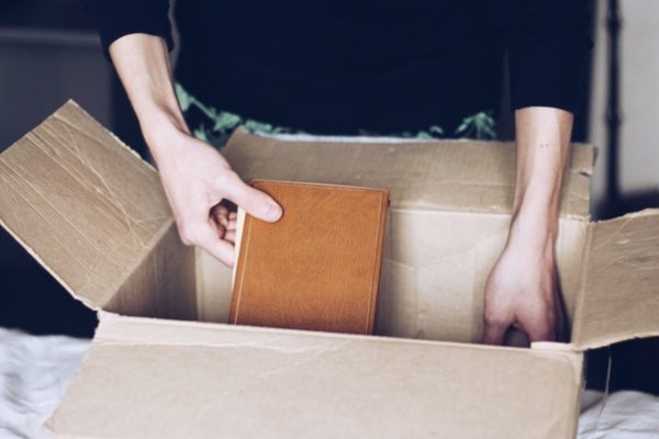 a woman placing a book inside a cardboard box